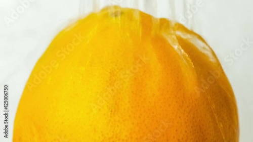 Clean clear water streaming down over orange fruit with vibrant citrus skin, includes sounds of flowiing liquid