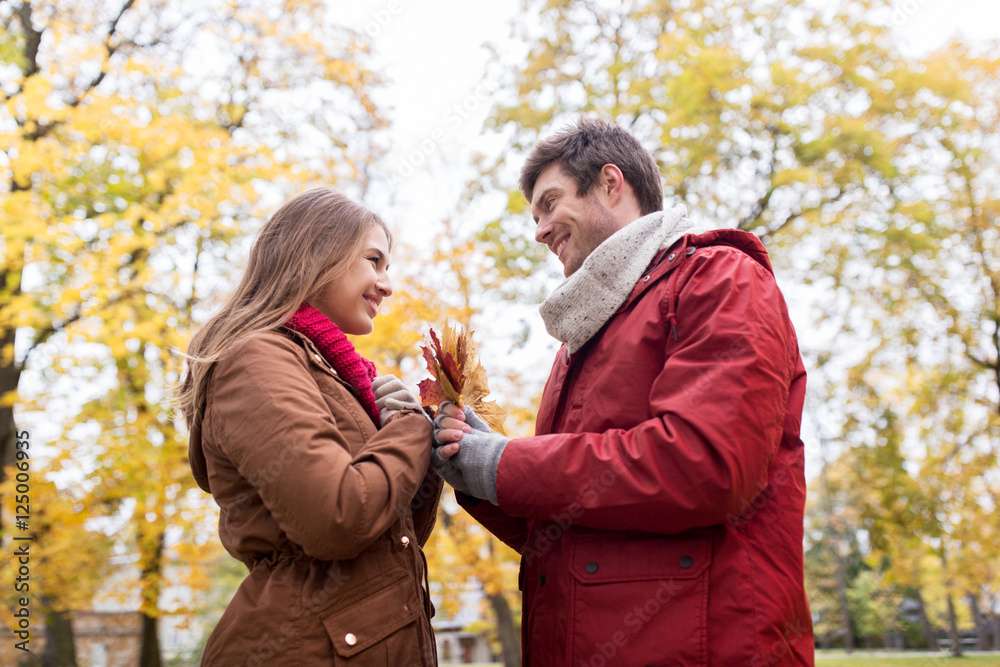Naklejka premium happy couple with maple leaves in autumn park