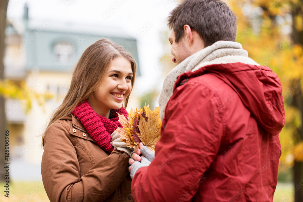 Obraz premium happy couple with maple leaves in autumn park