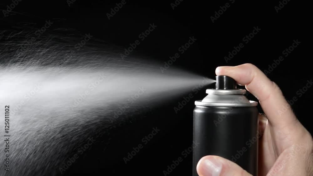 .A man depresses the button on an aerosol spray can, dispensing chemicals into the atmosphere.
