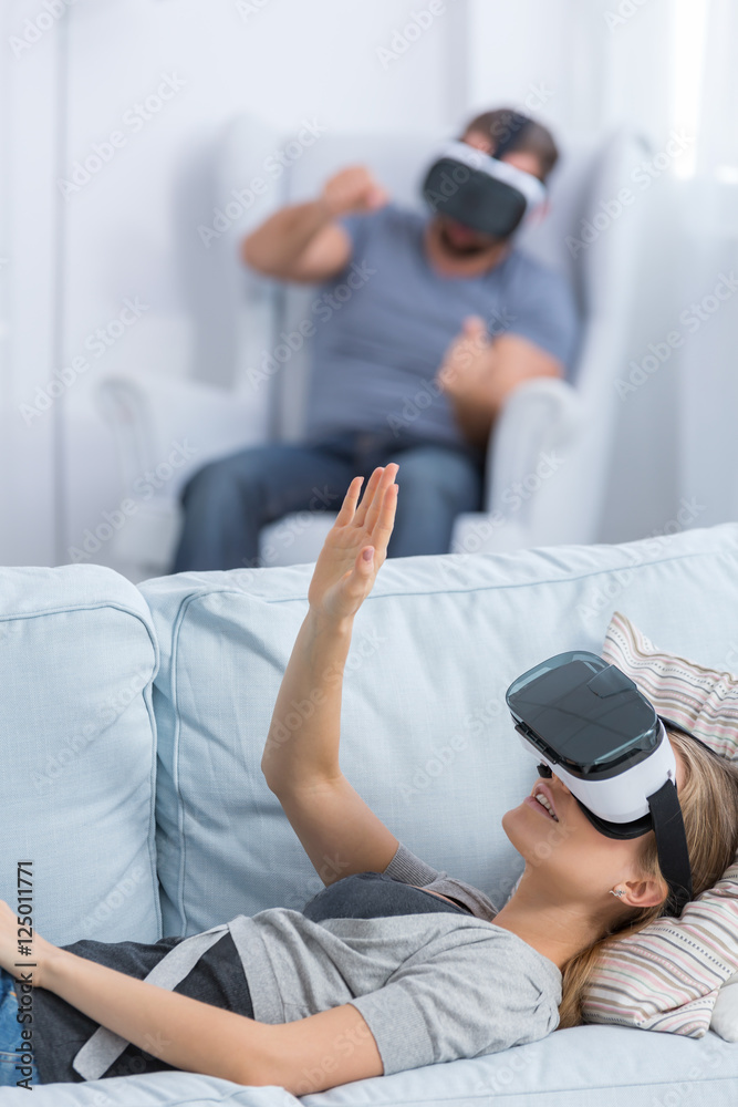 Woman lying on bed wearing VR glasses Woman lying on bed wearing VR glasses