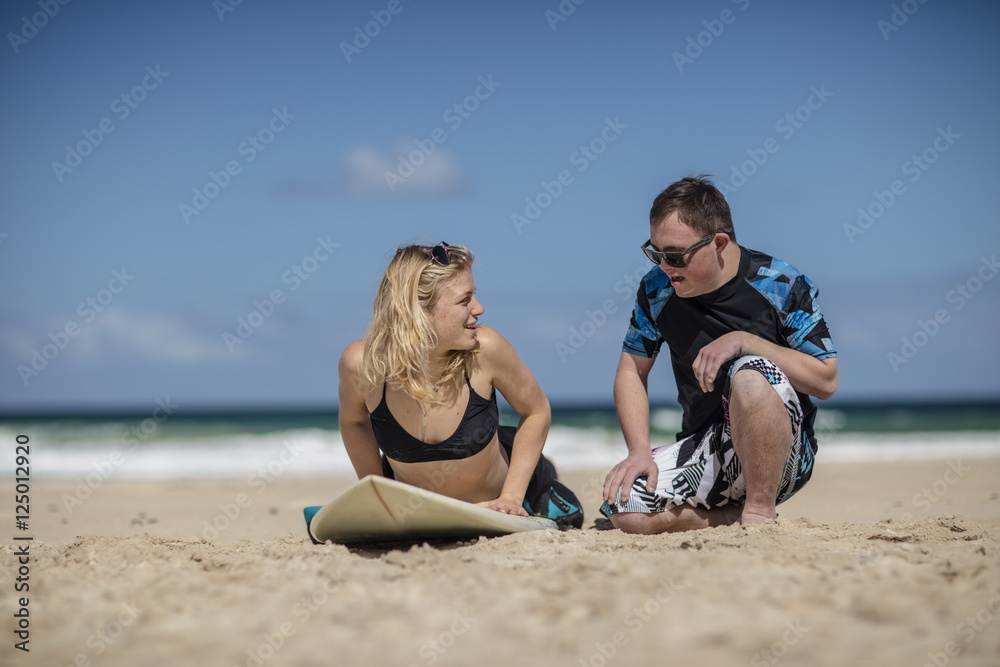 Teenage boy with down syndrome having surf lessons on beach Teenage boy with down syndrome having surf lessons on beach