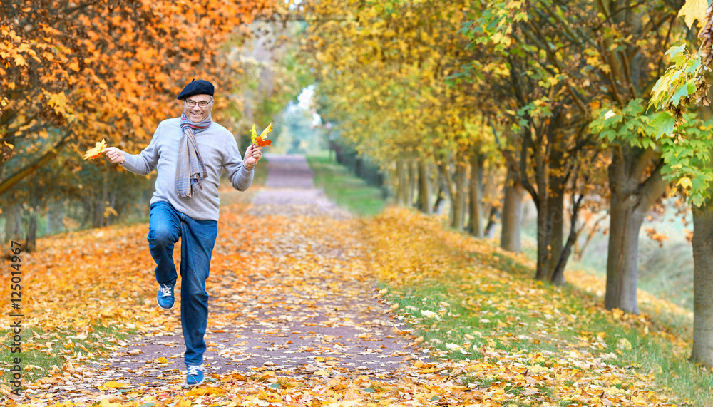 Fototapeta premium glücklich springender Senior im Herbst im Park, Lebensfreude