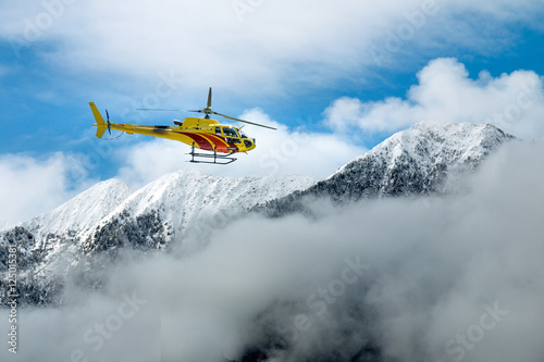 elicottero in volo tra lle montagne sopra le nuvole  photo