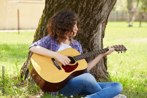 Woman playing guitar in park photo