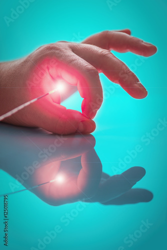 Bright light source on the end of the probe between big and index fingers  the left hand  the person
