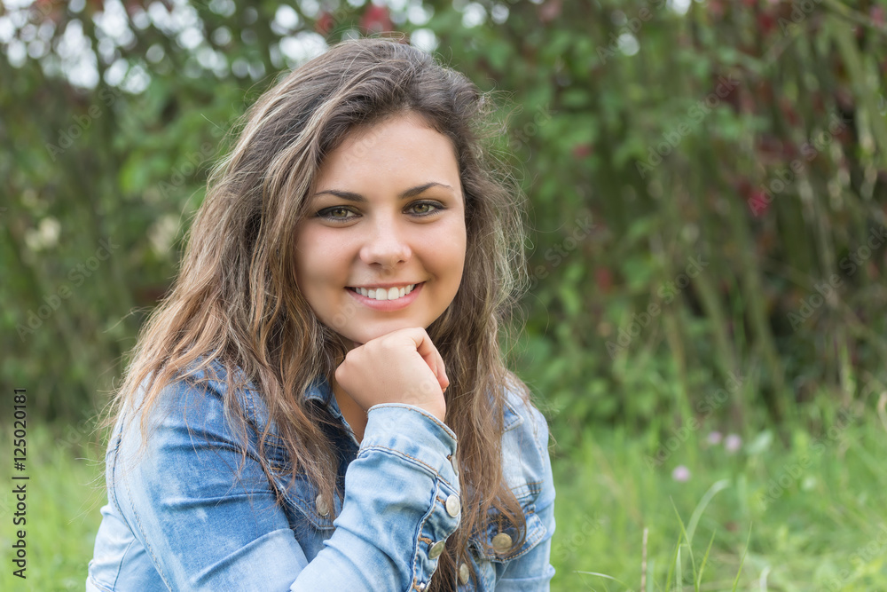 Smiling attractive long haired teenage girl is supporting her chin by hand looking at the camera. Smiling attractive long haired teenage girl is supporting her chin by hand looking at the camera.