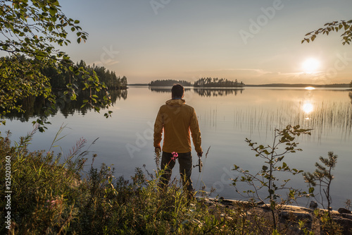 Man is fishing on the sunset lake