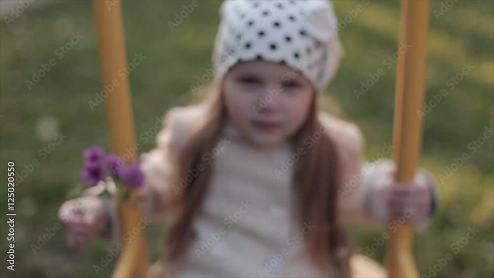 The little girl with flower sways on a swing The little girl with flower sways on a swing
