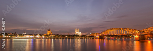 Illuminated Cologne Cathedral and bridge at night in Cologne, panoramic view