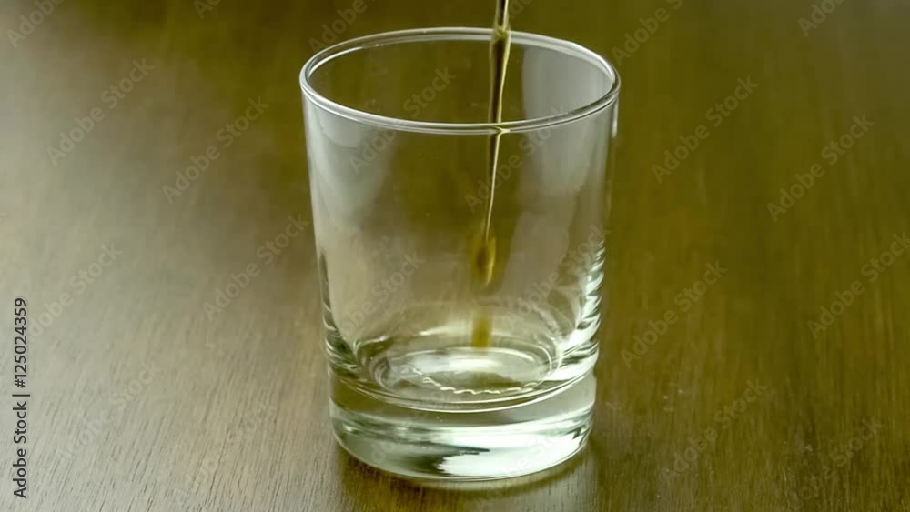Drink glass filling up with fizzy cola soft-drink against classic dark wood table, slow motion 30p Drink glass filling up with fizzy cola soft-drink against classic dark wood table, slow motion 30p