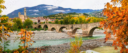 Foto Bobbio - one of the most beautiful villages of italy, Emilia Romagna, Medieval Ponte Gobbo arched bridge over stony Trebbia river