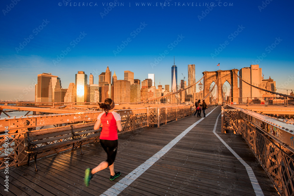 Fototapeta premium Fitness kobieta biegacz relaks po mieście działa i na zewnątrz w Nowym Jorku, USA. Dziewczyna patrzeje i cieszy się widok most brooklyński. Mieszane rasy azjatyckich kobiet rasy kaukaskiej modelu.