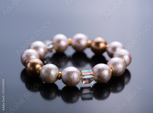 Pearl bracelet with crystals on a dark background. Beadwork.