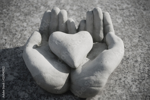 mains tenant un coeur sur une tombe au cimetière photo