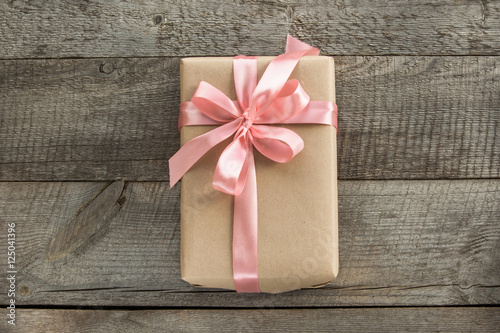 Fotografía Handmade present from wrapping paper and pastel pink bow and ribbon on wooden surface