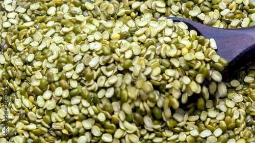 Wholesome organic mung dal beans scooping up with a large wooden spoon
