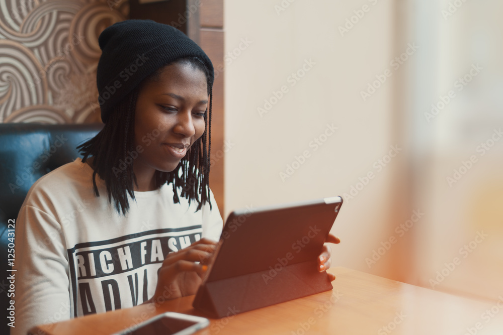 Beautiful black girl smiling and working on tablet in cafe Beautiful black girl smiling and working on tablet in cafe