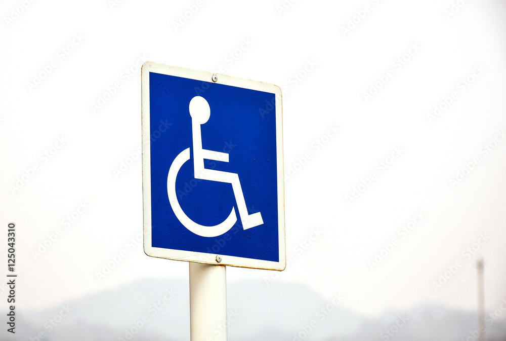 Standard handicapped people access sign with hazy sky in the background Standard handicapped people access sign with hazy sky in the background