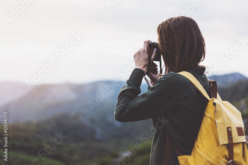 Tourist traveler photographer taking pictures of landscape on vintage photo camera on background valley view mockup sun flare, hipster girl with backpack enjoying sunset on peak of foggy mountain