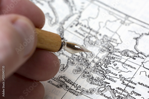 A person is drawing a historical map with an ink pen.