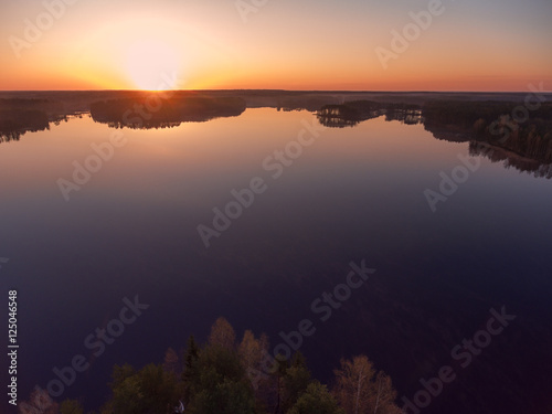 Beautiful sunrise over woods and islands of lake, aerial view over trees tops