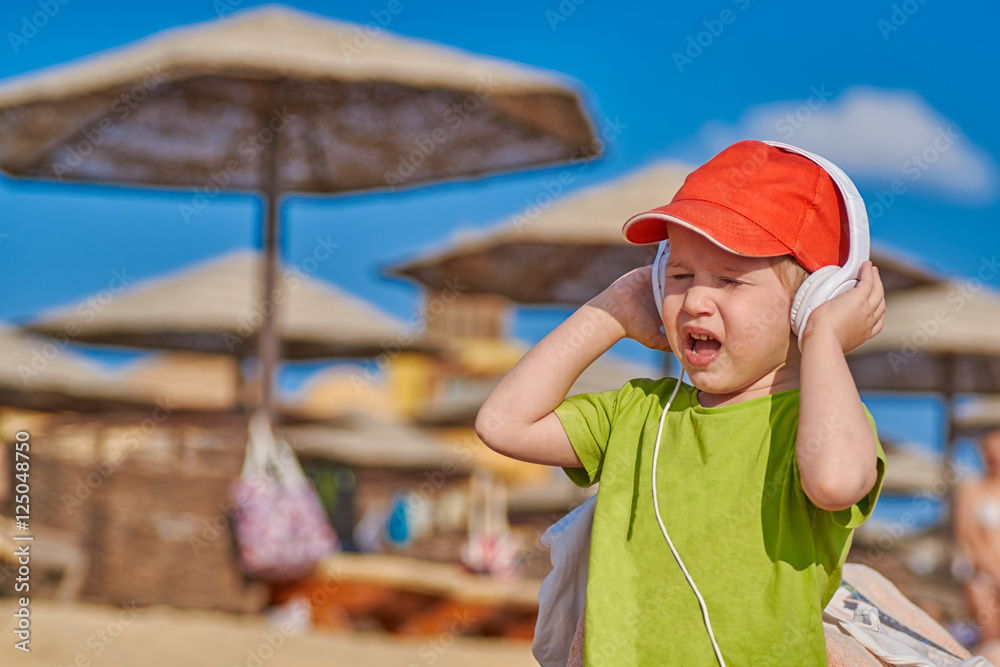 Child Boy Enjoying Music in Headphones at the Beach