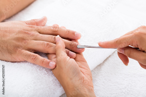 Manicurist Removing Cuticle From Person's Nail