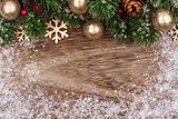 Christmas top border with gold ornaments, branches and snow frame on a rustic wood background