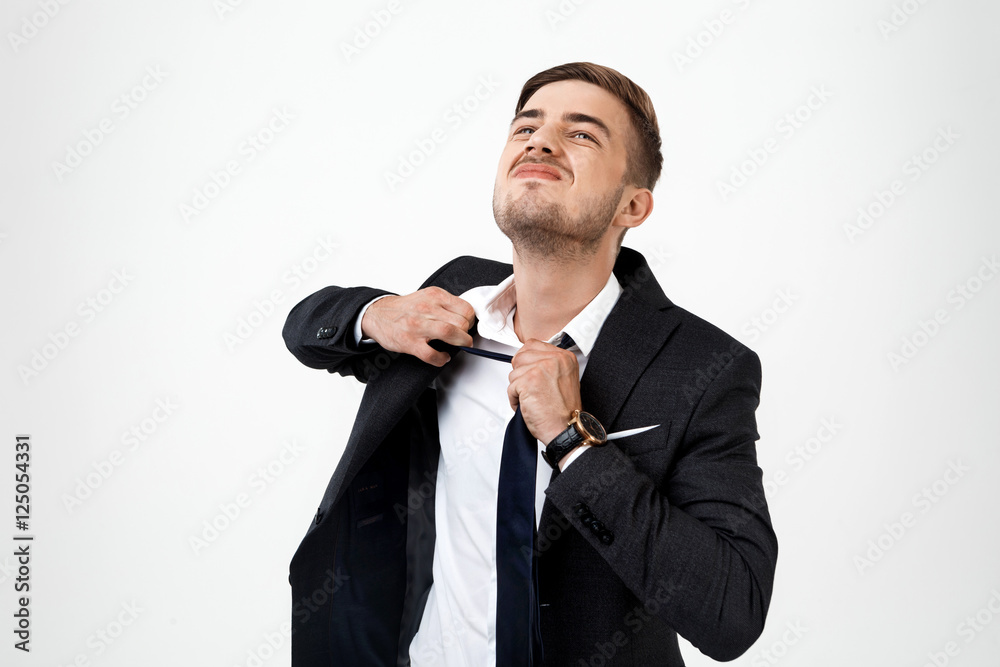 Naklejka premium Young successful businessman taking tie off over white background.