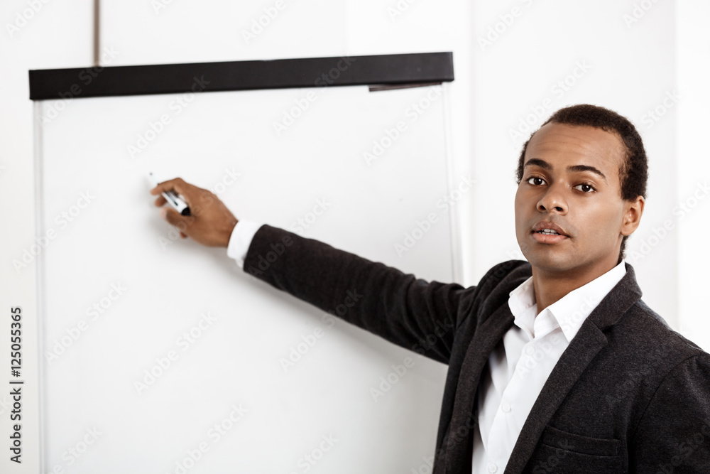 Young successful african businessman writing on board in office. Young successful african businessman writing on board in office.