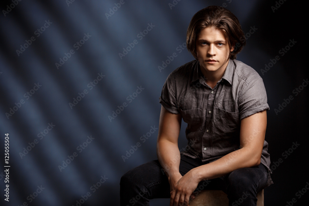Calm young handsome man looking at camera over black background. Calm young handsome man looking at camera over black background.