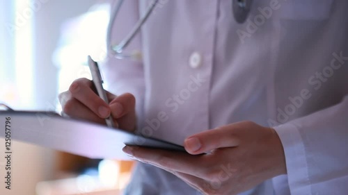 Close up of doctor's hands writing on medical chart in the hospital