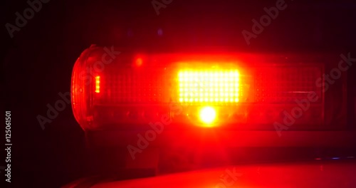 Police lights flashing and passing by cars on street
