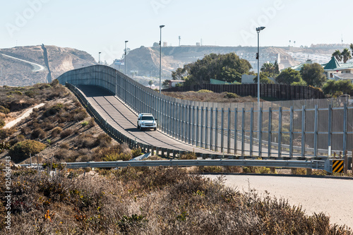 San Diego, California and Tijuana, Mexico international border wall with border patrol vehicle.  photo