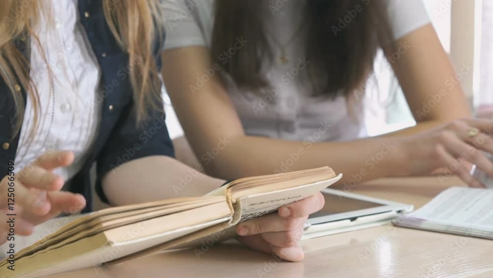 Girl talking each other and flipping the textbooks Girl talking each other and flipping the textbooks