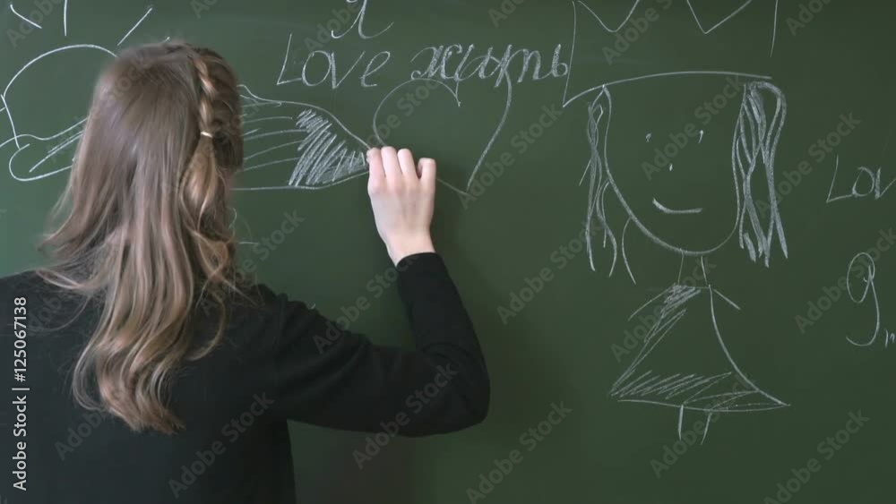 A young student writes with chalk on a blackboard A young student writes with chalk on a blackboard