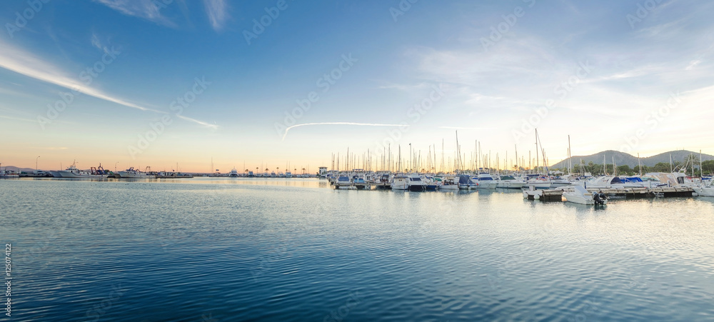 Large yacht harbor in purple sunset light, luxury summer cruise, sailboats in sunrise, leisure time, active life, vacation and holidays concept Yachts and their reflection in the city's port