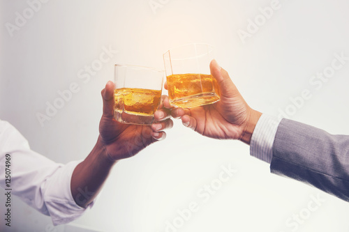 Two businessman in shirt and tie talking to each other while drinking whisky after office hour.