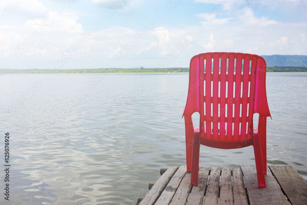Fototapeta premium red chair on wooden bridge near sea beach