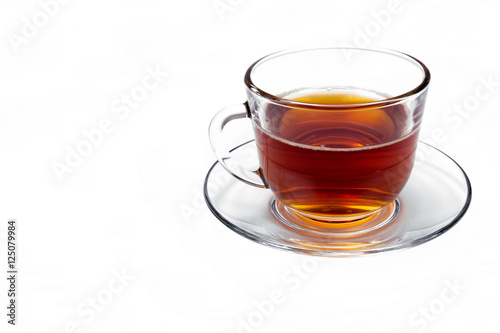transparent glass cup with tea on a saucer isolated