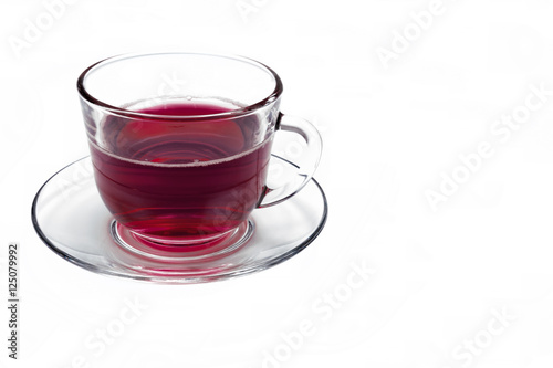 transparent glass cup with Hibiscus tea on a saucer isolated