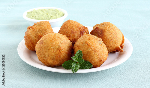Indian vegetarian food aloo vada, a traditional and popular snack, made from deep frying portions of chickpea flour, vegetables and mashed potato batter.