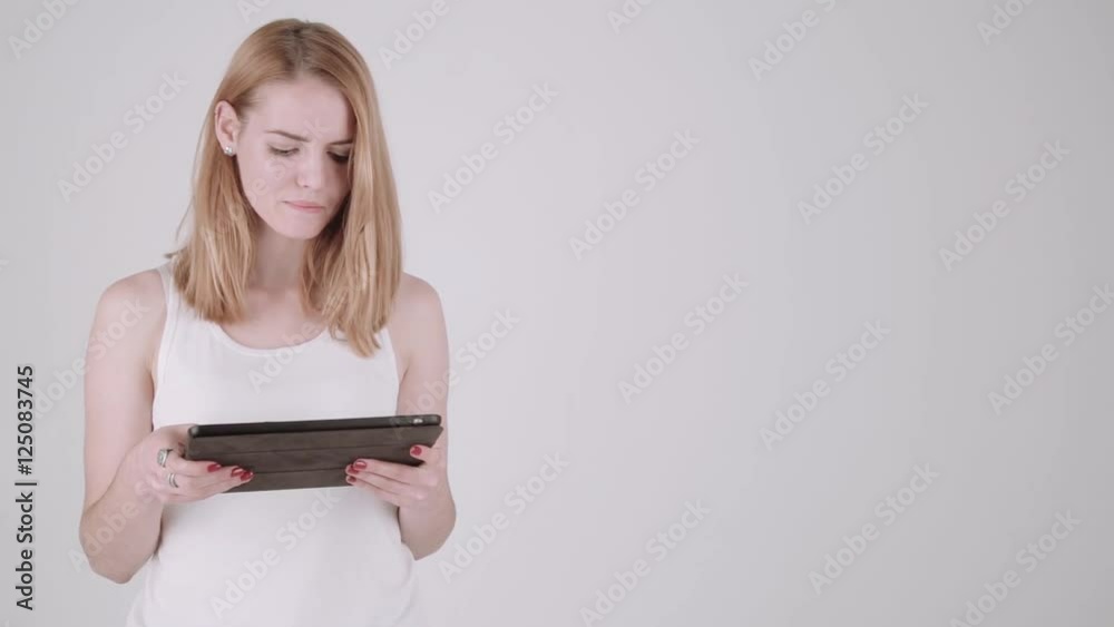 Happy woman standing with table PC computer over light gray background. Copy space text. Properly color corrected version Happy woman standing with table PC computer over light gray background. Copy space text. Properly color corrected version