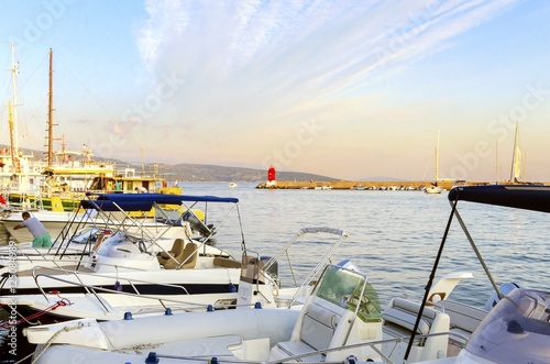 The red lighthouse, mole at Krk town, Croatia marina and boats docked at the harbour pier at sunset. A small cylindrical tower at the biggest port of the island.