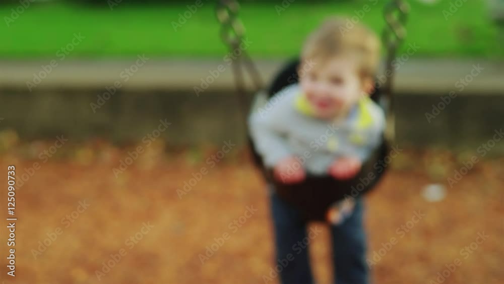 Adorable little boy on a swing in slow motion, with a big smile on his face Adorable little boy on a swing in slow motion, with a big smile on his face