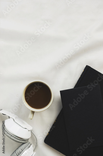 cup of coffee and book on white bed. over light and vintage tone photo