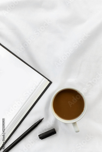 cup of coffee with open book on white bed. over light and vintage tone photo