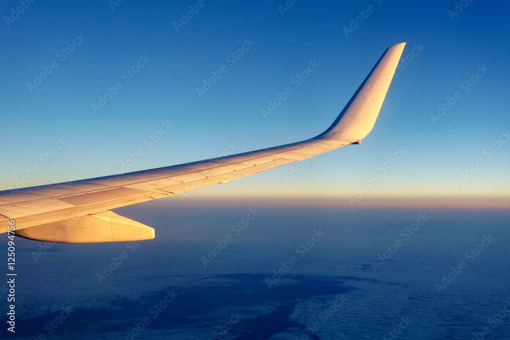 Passenger aircraft wing against clear blue sky, purple split toning colors Passenger aircraft wing against clear blue sky, purple split toning colors