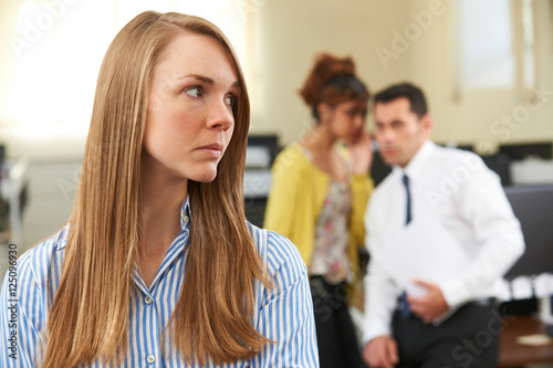 Businesswoman Being Gossiped About By Colleagues In Office photo